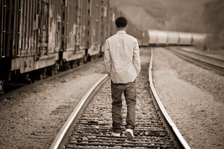 Photo of boy walking away from camera on train track
