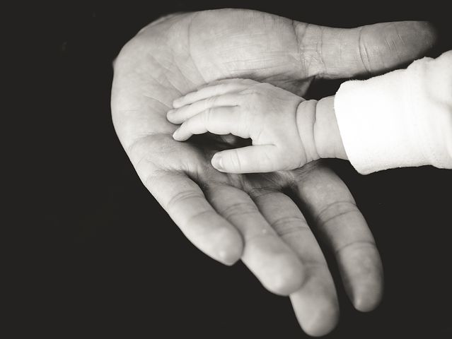 Photo of a baby's hand resting on an adults hand