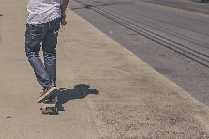 Photo of teen skateboarding down a sidewalk